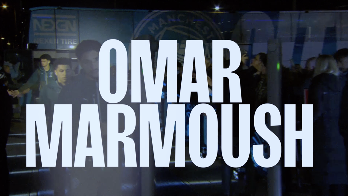 Text overlay of 'Omar Marmoush' in bold letters, blurred faces in the background, with Manchester City logo and bus visible.