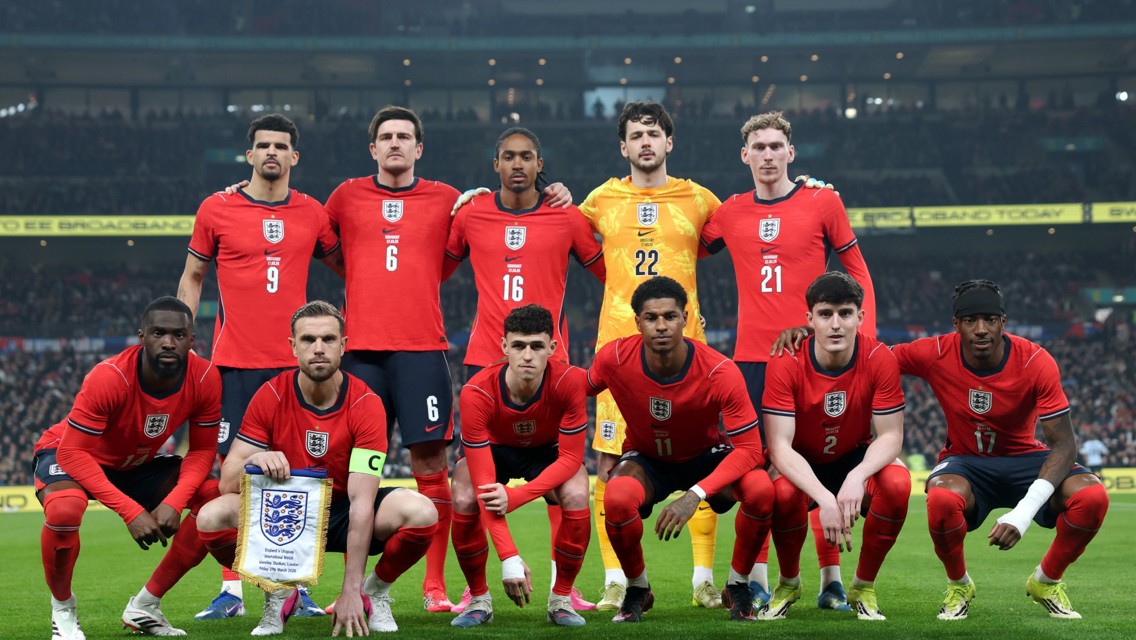 The England men's football team poses for a group photo on the field in their red jerseys.