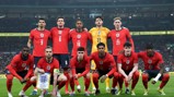The England men's football team poses for a group photo on the field in their red jerseys.