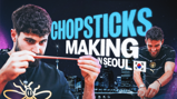 A banner image featuring two individuals making chopsticks in Seoul. The text 'Chopsticks Making in Seoul' is prominent. The individuals are focused on their task, with a background of Seoul's skyline.