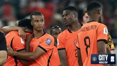 Dutch football players wearing orange jerseys with 'GRAVENBERCH' visible on one shirt, standing together at a World Cup event, with a 'CITY World Cup' logo in the corner.