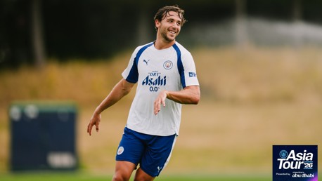 Manchester City football player in training wearing a jersey with 'Asia Tour '26' logo.