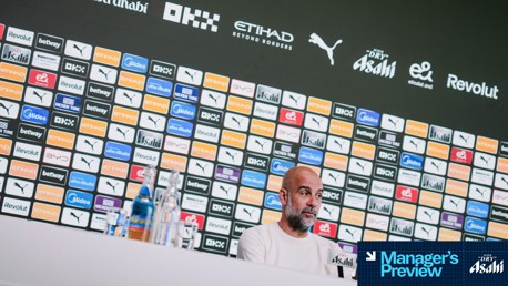 A press conference setup with various brand logos displayed on a wall behind a person. The brands include Puma, Betway, Etihad, OKX, and Dry Asahi.