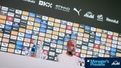 A press conference setup with various brand logos displayed on a wall behind a person. The brands include Puma, Betway, Etihad, OKX, and Dry Asahi.