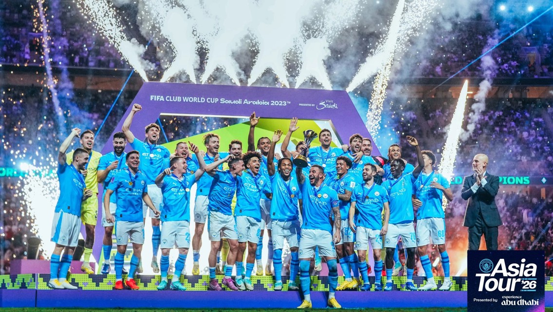Football team celebrating winning the FIFA Club World Cup 2023 in Saudi Arabia. Players in blue uniforms holding a trophy amid fireworks and confetti.
