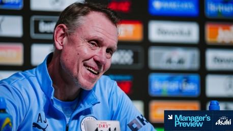 A press conference setting featuring a person in a Manchester City top with sponsor logos in the background. Text reading 'Manager's Preview' is present.