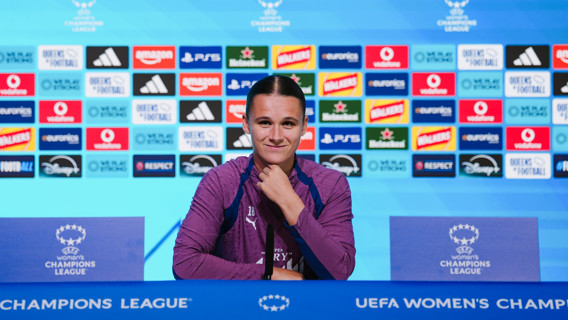 Person at a press conference sitting at a table with UEFA Women's Champions League branding.