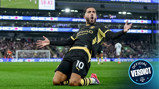 A football player wearing a black and yellow kit slides on his knees celebrating a goal, with a stadium crowd in the background. There is a digital scoreboard displaying 58:43.