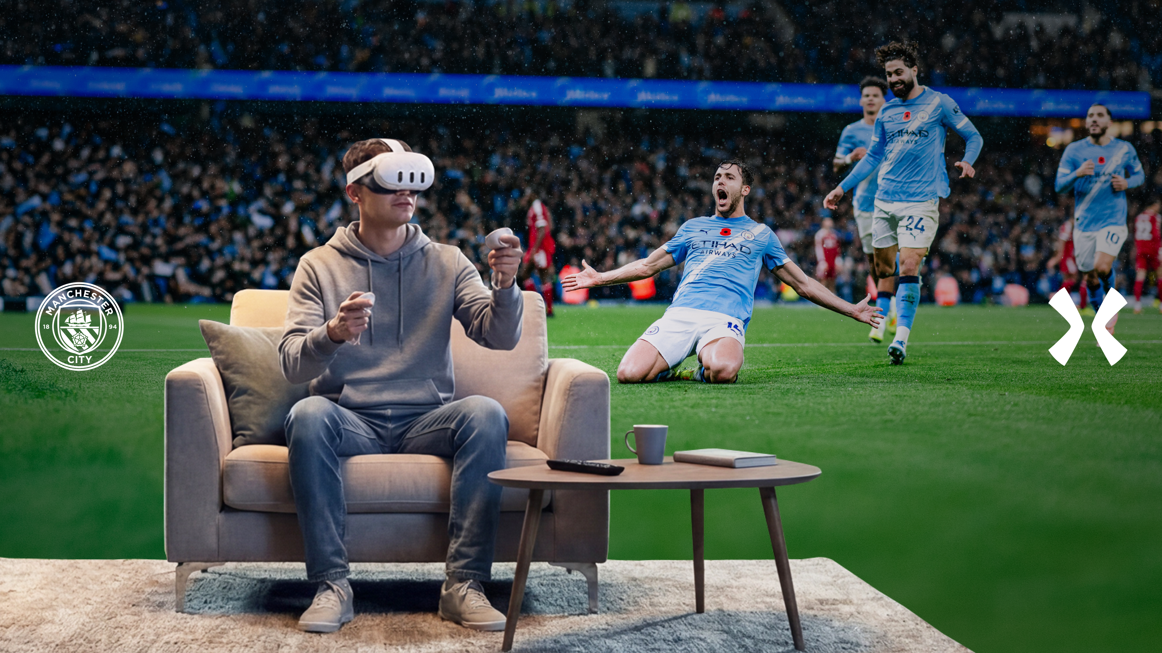 A person wearing a VR headset sits on a couch, seemingly experiencing a soccer match. In the background, Manchester City players celebrate on the pitch.