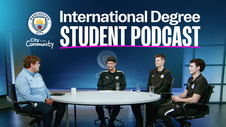 Manchester City International Degree Student Podcast setting. Four people seated at a round table on a stage, under a large banner with a Manchester City crest and podcast title.