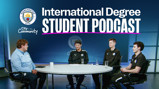 Manchester City International Degree Student Podcast setting. Four people seated at a round table on a stage, under a large banner with a Manchester City crest and podcast title.