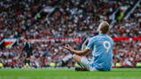 A player in a light blue Manchester City jersey with the name 'Haaland' and number '9' sits on the field in a meditation pose during a match.