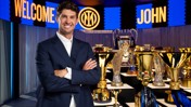 Man smiling in front of a trophy display. Background says 'Welcome John' with Inter logo.