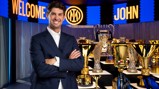 Man smiling in front of a trophy display. Background says 'Welcome John' with Inter logo.