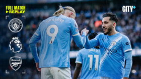 Manchester City players shaking hands during a Premier League match against Arsenal. Visible logos include Manchester City and Arsenal crests. The image promotes a full match replay on City+.