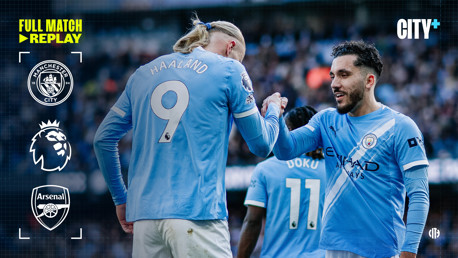 Manchester City players shaking hands during a Premier League match against Arsenal. Visible logos include Manchester City and Arsenal crests. The image promotes a full match replay on City+.