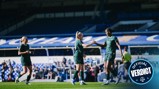 Manchester City women's team players on a soccer field celebrating a goal with a handshake, wearing green jerseys with Etihad sponsor, in a stadium with blue seating.