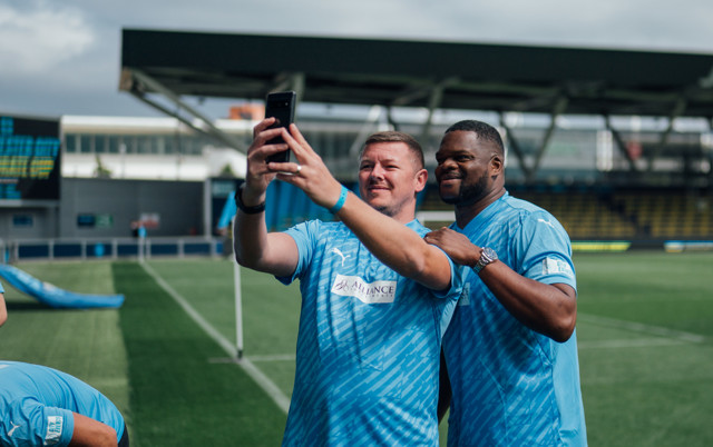 Two football players take a selfie on a football field.
