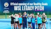 Group of young footballers and a coach standing on a blue sports pitch with Manchester City community logos. Text reads 'Official opening of our Healthy Goals WSL Legacy Pitch.'