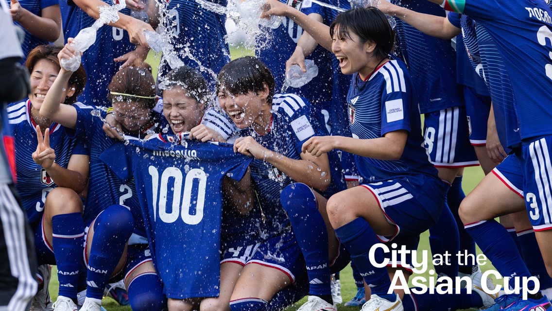 Japanese female soccer team celebrating at the Asian Cup. Players in blue jerseys with number 100, pouring water in celebration.