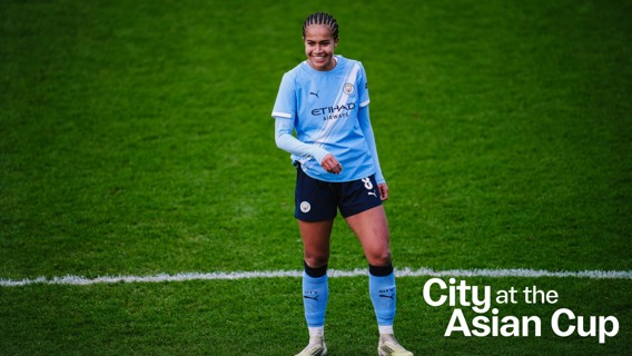 A football player wearing Manchester City's light blue kit stands on the soccer field during the Asian Cup event. The player wears jersey number 8.