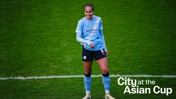 A football player wearing Manchester City's light blue kit stands on the soccer field during the Asian Cup event. The player wears jersey number 8.