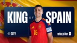 A soccer player in a Spanish jersey is standing in front of a banner reading 'King of Spain' with 'World Cup' and 'City' logos.