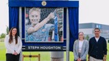Three people are standing beside a mosaic depicting a football player with a trophy. The mosaic features the name 'Steph Houghton'.