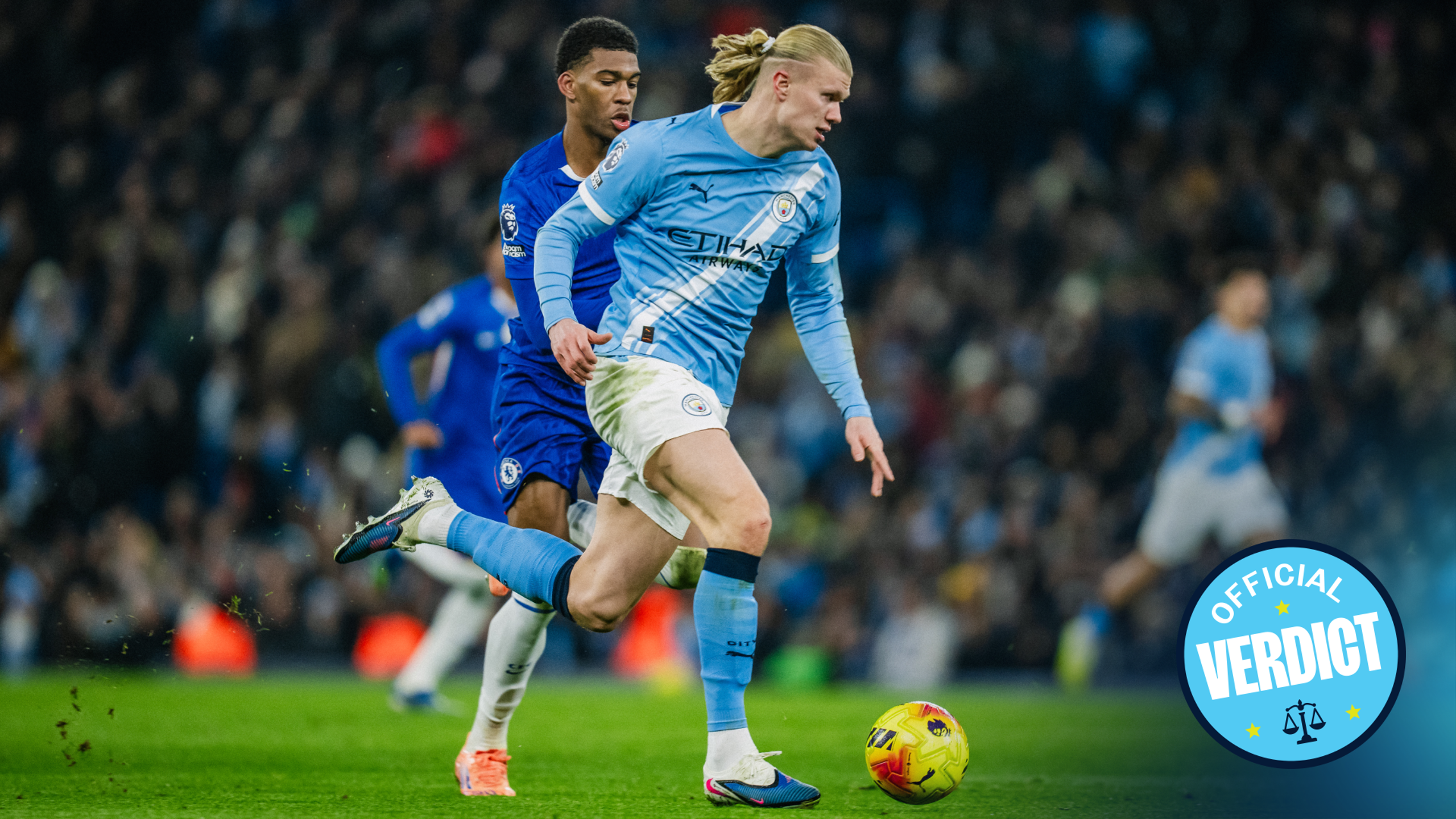 Blurred image depicting two soccer players in action during a match between Manchester City and Chelsea, with the official verdict logo visible.