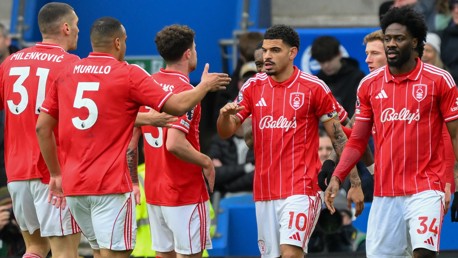 Nottingham Forest players celebrating in red and white striped jerseys with sponsor 'Bally's'.