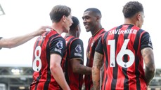 A group of AFC Bournemouth players wearing red and black jerseys, celebrating. Two jerseys have names 'Scott' and 'Tavernier' with numbers 8 and 16.