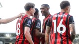 A group of AFC Bournemouth players wearing red and black jerseys, celebrating. Two jerseys have names 'Scott' and 'Tavernier' with numbers 8 and 16.