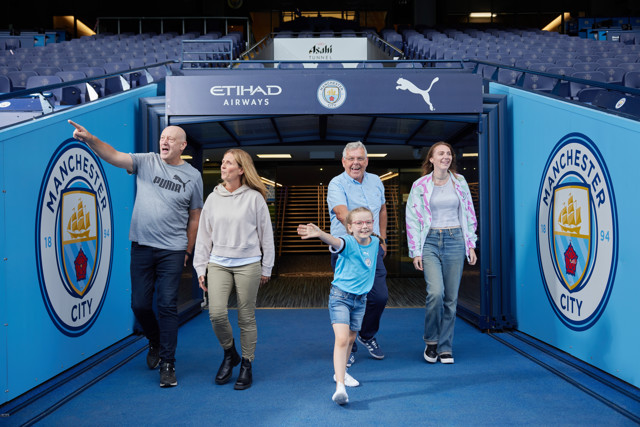 A group of people walking through the tunnel at Etihad Stadium, home of Manchester City.