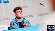 A person holding a microphone at a press conference for the Asia Tour '26. The background displays logos and text including 'Coupang' and 'Puma'.