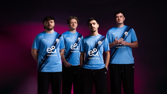 Four individuals wearing Manchester City Esports blue jerseys stand together. The jerseys have the Etisalat and Puma logos.