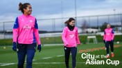 Three players from Manchester City Women's team in pink training kits on a field with the text 'City at the Asian Cup'.