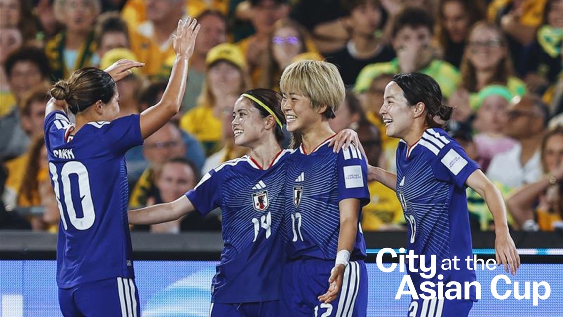 Four players in blue football kits with Japan emblem celebrate on the field. The text 'City at the Asian Cup' is visible on the image.
