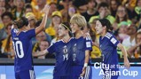 Four players in blue football kits with Japan emblem celebrate on the field. The text 'City at the Asian Cup' is visible on the image.