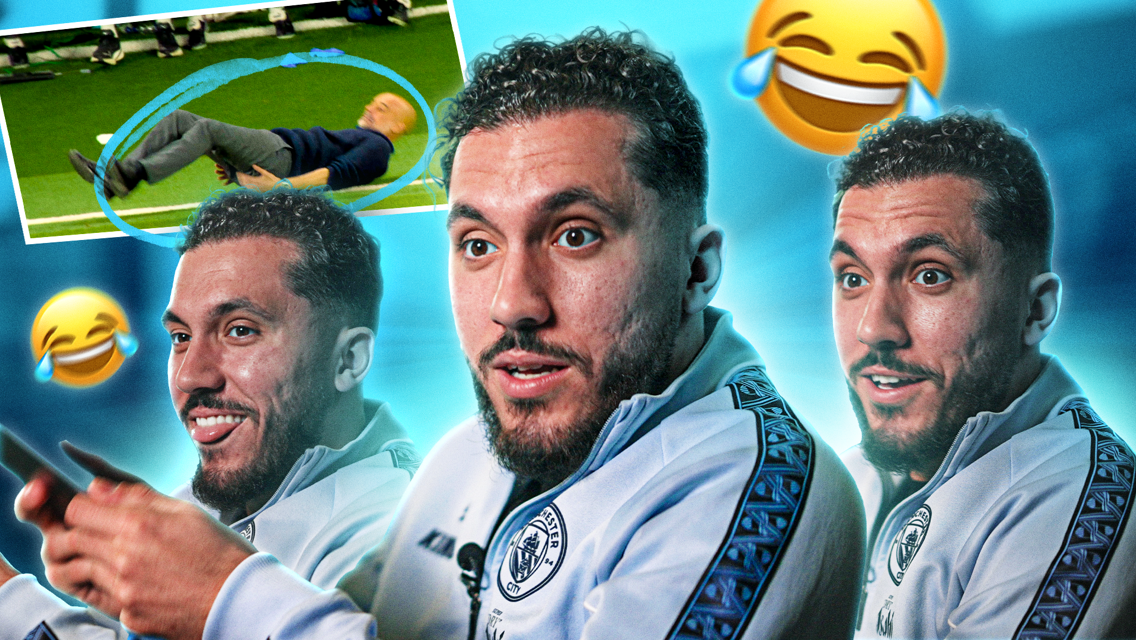 A football player appearing amused during an interview. The background includes a photo of an older man lying on the grass, surrounded by laughing emojis. The player is wearing a Manchester City jacket.