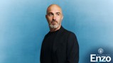 A man with a bald head and grey beard wearing a black jacket against a blue background. Text reads 'Welcome back Enzo' with a Manchester City logo.
