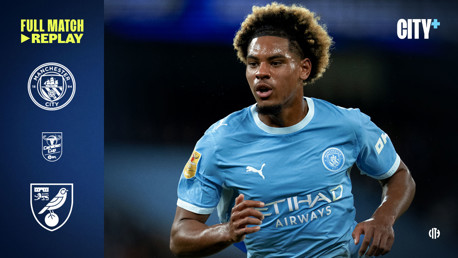 Manchester City player in action wearing team kit during a match replay banner. Logos for Manchester City, Carabao Cup, and Norwich City are visible along with text 'Full Match Replay' and 'CITY+'.