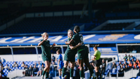 Football players in green jerseys celebrating on the field with a scoreboard in the background.