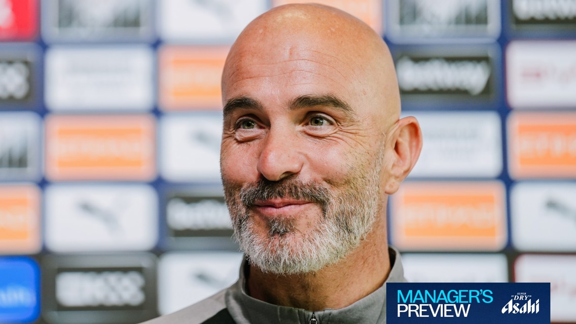 A bald man with a beard, smiling in front of a backdrop with logos. The image features a 'Manager's Preview' text and a sponsored logo.