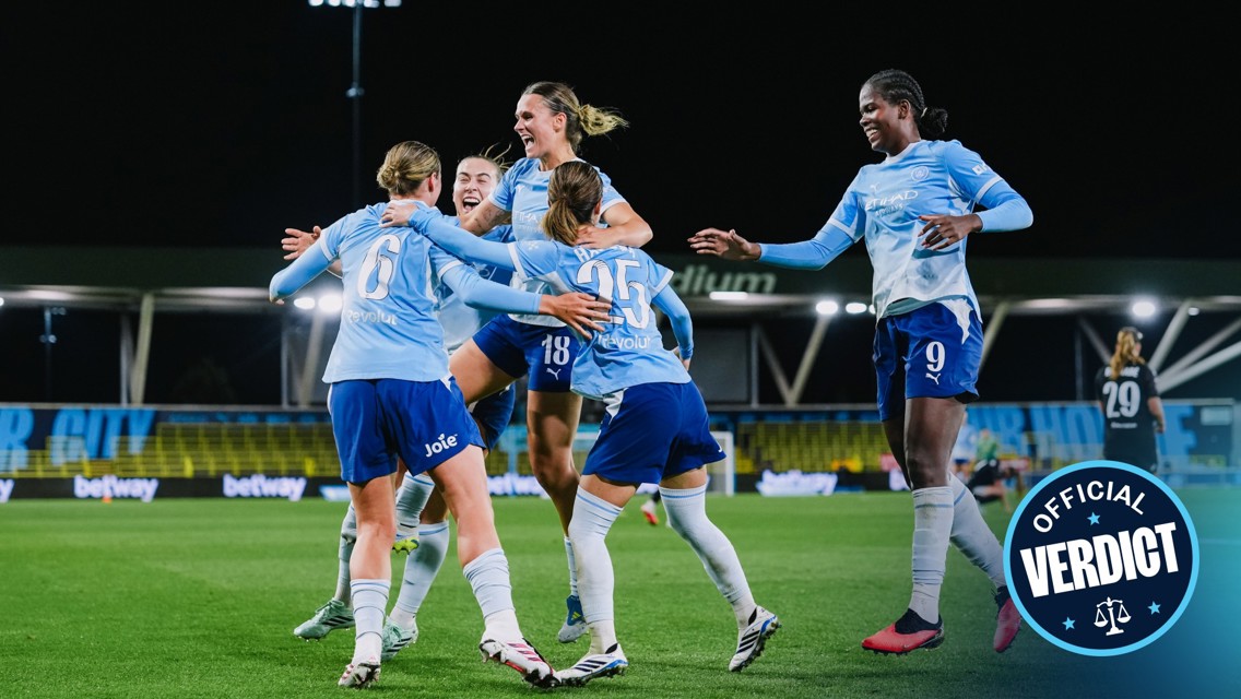 A group of female soccer players in light blue jerseys celebrate a goal on the field. The scene is full of excitement and camaraderie under stadium lights with an 'Official Verdict' badge visible on the right.