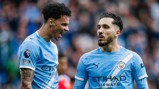 Two soccer players in Manchester City jerseys speaking on the field. Jerseys feature the team logo and sponsor branding.