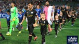 Manchester City players enter the field during the Asia Tour 2026, accompanied by children in matching uniforms, with stadium crowd in the background.