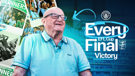 A person in front of EFL Cup final victory graphics for Manchester City, featuring past winning moments.