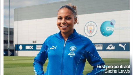 A person in a blue Manchester City tracksuit stands smiling on a field. The background shows the Manchester City logo and the text 'First pro contract Sacha Lewis' displayed on the image.