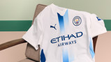 A white Manchester City football jersey with blue accents, featuring the Puma logo and Etihad Airways sponsor. The jersey displays the Manchester City crest.