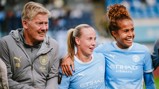 Three individuals, including two wearing Manchester City women's football kits and a coach, smiling and posing together on the field.
